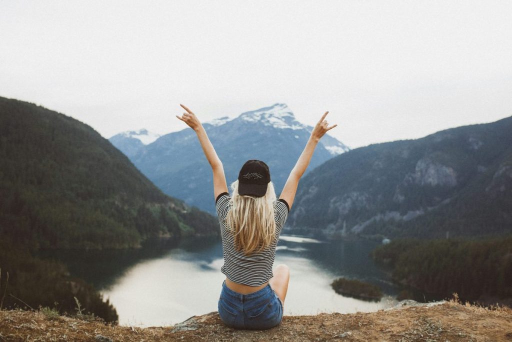 having no friends is ok. woman sitting alone on mountain, happy with her freedom.